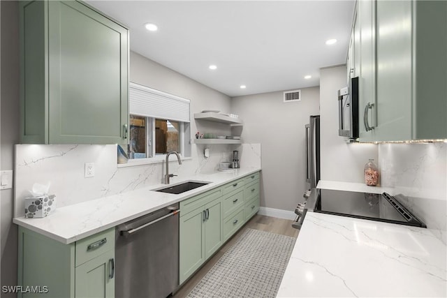 kitchen featuring light stone counters, green cabinetry, appliances with stainless steel finishes, and sink