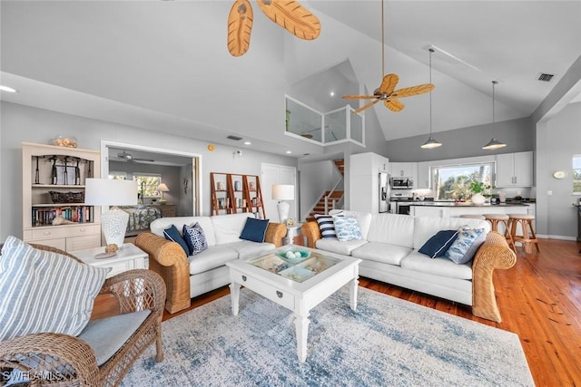 living room with ceiling fan, hardwood / wood-style floors, and high vaulted ceiling