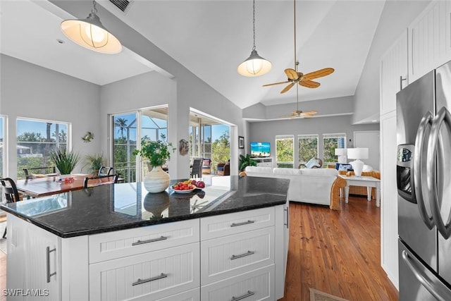 kitchen featuring stainless steel refrigerator with ice dispenser, white cabinetry, a center island, and dark stone countertops