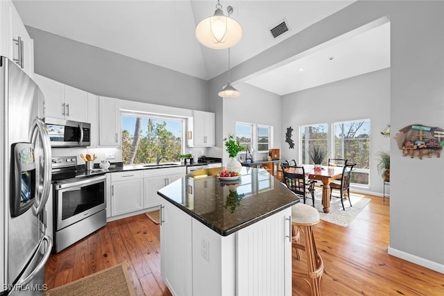 kitchen featuring sink, appliances with stainless steel finishes, hanging light fixtures, white cabinets, and a kitchen island