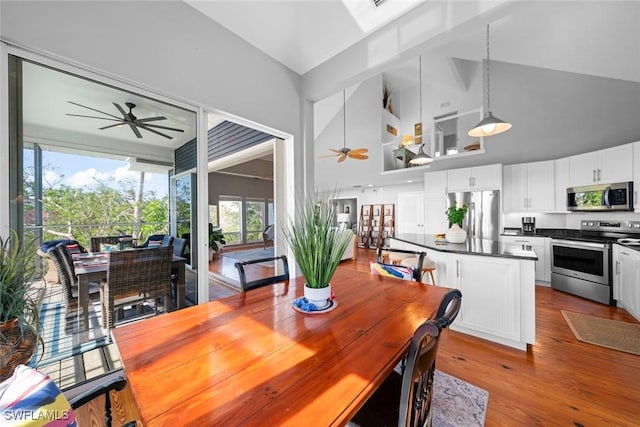 dining area featuring ceiling fan, high vaulted ceiling, and light hardwood / wood-style flooring