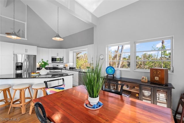 dining room featuring sink, high vaulted ceiling, and light hardwood / wood-style flooring