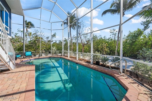 view of swimming pool featuring a patio area and glass enclosure