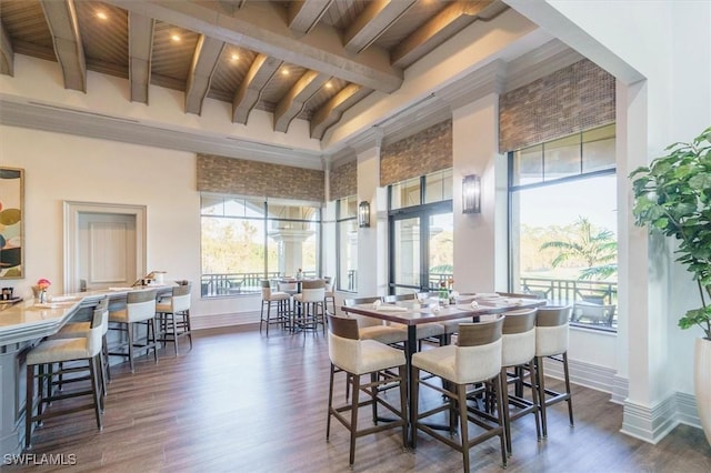 dining area with dark wood-type flooring, beam ceiling, and a high ceiling