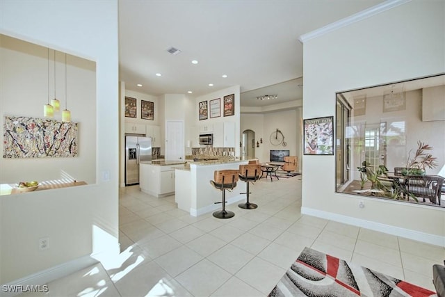 kitchen featuring hanging light fixtures, stainless steel appliances, a kitchen breakfast bar, white cabinets, and kitchen peninsula