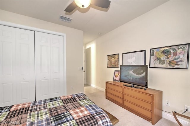 bedroom with ceiling fan, light carpet, and a closet