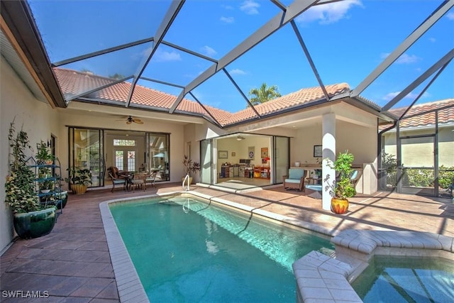 rear view of property with ceiling fan, a patio area, and glass enclosure