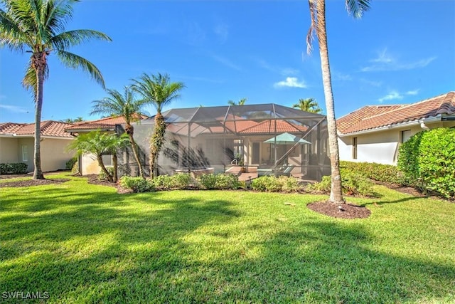 rear view of property with a yard and a lanai