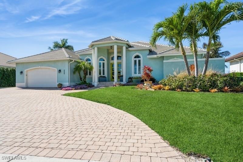 mediterranean / spanish-style home featuring a garage and a front lawn