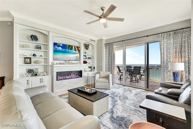 living room with built in shelves, ceiling fan, and ornamental molding