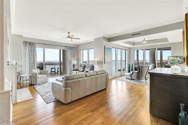 living room with ceiling fan, a water view, crown molding, and light hardwood / wood-style floors