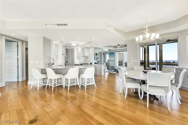 dining space with light hardwood / wood-style floors and a chandelier