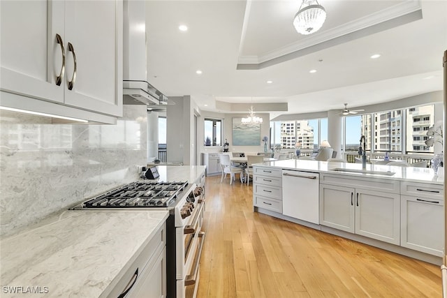 kitchen with a tray ceiling, sink, range with two ovens, light hardwood / wood-style floors, and white dishwasher