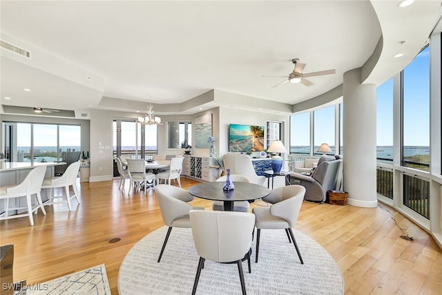 dining area with ceiling fan with notable chandelier and light hardwood / wood-style flooring