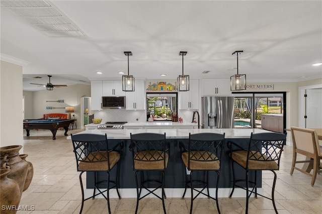 kitchen with decorative light fixtures, a kitchen breakfast bar, stainless steel appliances, decorative backsplash, and white cabinets