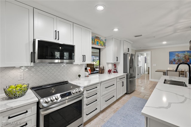 kitchen featuring sink, white cabinetry, crown molding, light stone counters, and appliances with stainless steel finishes