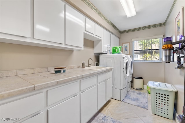 laundry room featuring sink, light tile patterned floors, washing machine and dryer, and cabinets