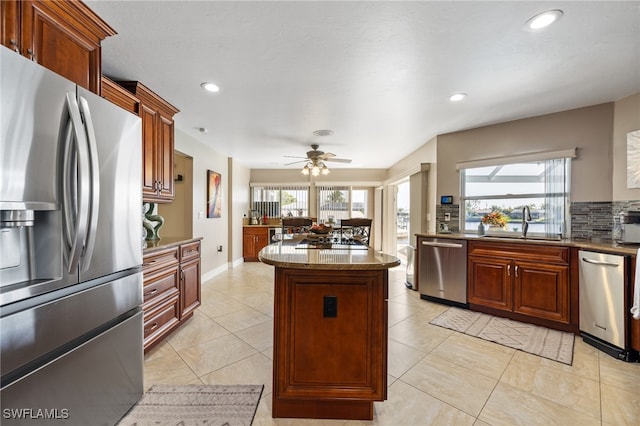 kitchen featuring sink, light tile patterned floors, appliances with stainless steel finishes, ceiling fan, and backsplash