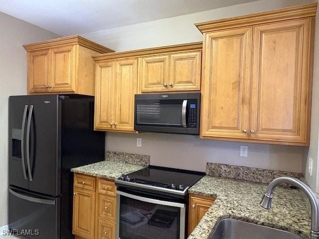 kitchen featuring stainless steel electric stove, sink, light stone counters, and black refrigerator with ice dispenser