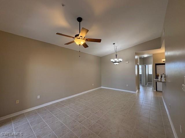 empty room with lofted ceiling, ceiling fan with notable chandelier, and light tile patterned floors