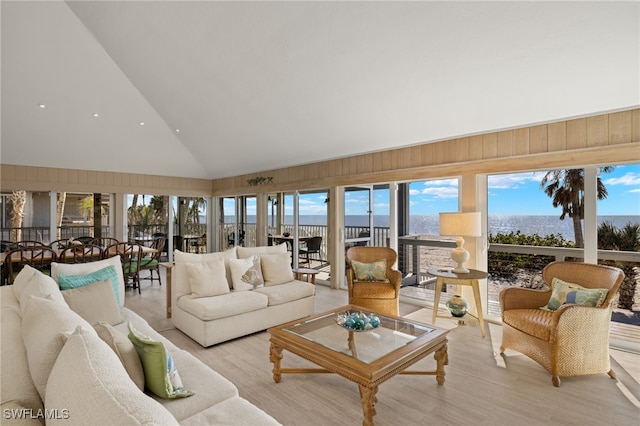 living room with light hardwood / wood-style flooring, high vaulted ceiling, and wood walls