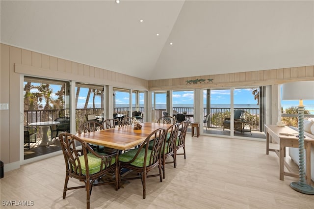 dining area featuring high vaulted ceiling and light hardwood / wood-style flooring