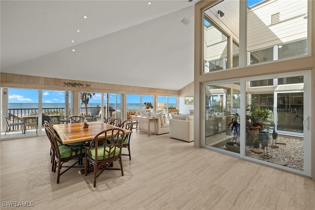 dining space featuring a water view and high vaulted ceiling