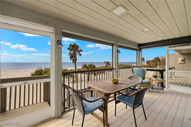 sunroom / solarium with a view of the beach, wood ceiling, and a water view