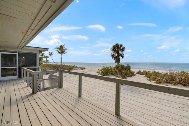 wooden terrace featuring a water view and a view of the beach