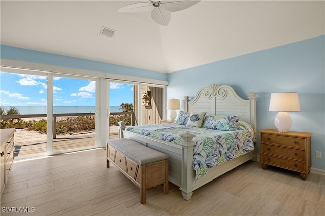 bedroom with access to exterior, light wood-type flooring, high vaulted ceiling, and a water view