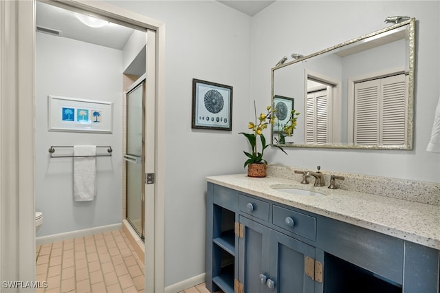 bathroom featuring a shower with door, vanity, and toilet