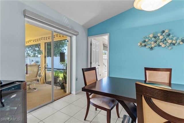 tiled dining room featuring vaulted ceiling