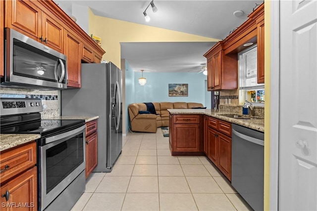 kitchen featuring lofted ceiling, sink, light tile patterned floors, stainless steel appliances, and tasteful backsplash