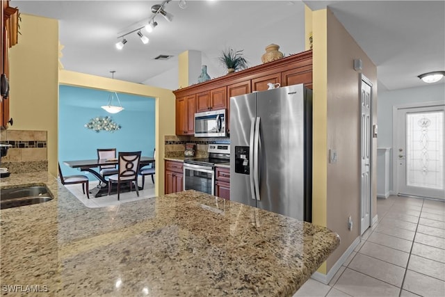 kitchen featuring appliances with stainless steel finishes, decorative light fixtures, kitchen peninsula, and backsplash