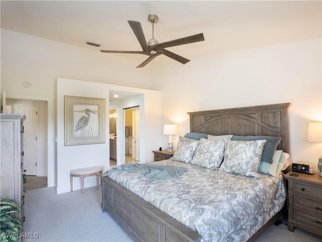 bedroom featuring ceiling fan, ensuite bath, and light colored carpet