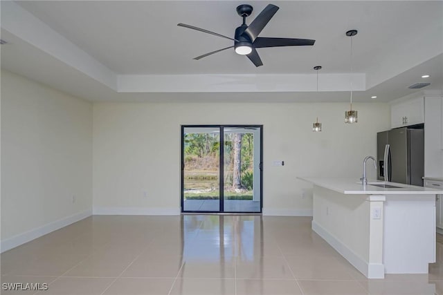 kitchen featuring light countertops, a tray ceiling, stainless steel fridge, and white cabinets