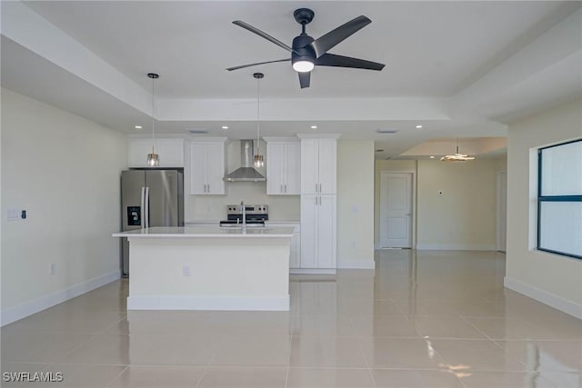 kitchen featuring stainless steel fridge, white cabinets, an island with sink, light countertops, and wall chimney range hood