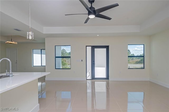 unfurnished room with a tray ceiling, light tile patterned flooring, and plenty of natural light