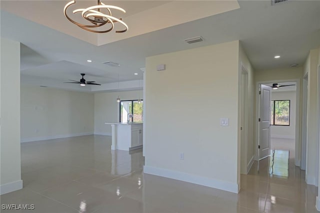 empty room featuring recessed lighting, a raised ceiling, light tile patterned flooring, baseboards, and ceiling fan with notable chandelier