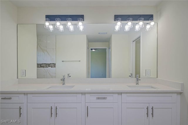 full bathroom with tiled shower, a sink, and double vanity