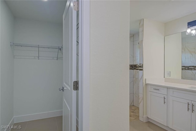 full bathroom featuring tile patterned floors, a spacious closet, baseboards, and vanity