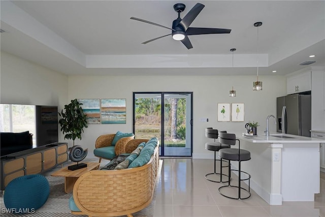 living room featuring light tile patterned floors, ceiling fan, a tray ceiling, and recessed lighting