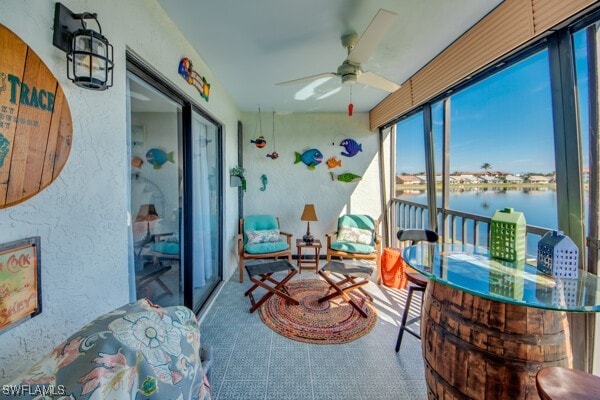 sunroom / solarium featuring a water view and a ceiling fan