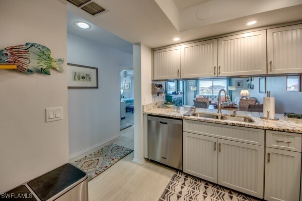 kitchen featuring light wood finished floors, recessed lighting, a sink, light stone countertops, and dishwasher