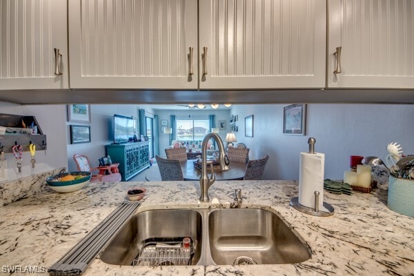 kitchen featuring white cabinetry, light stone counters, and a sink