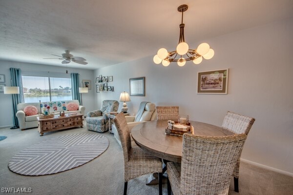 carpeted dining room with baseboards and ceiling fan with notable chandelier