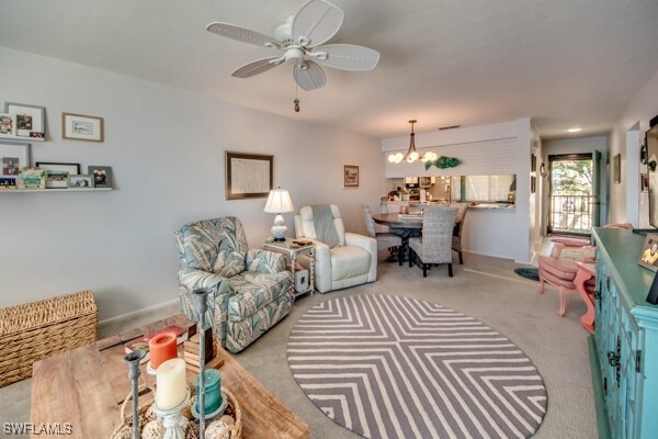 living area featuring carpet floors and ceiling fan with notable chandelier