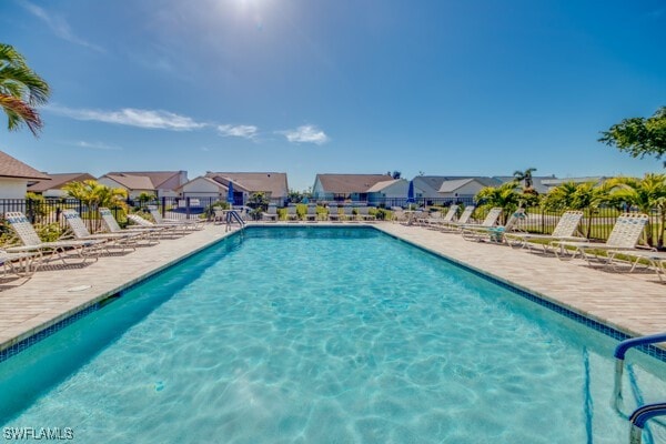 community pool featuring a patio area, fence, and a residential view