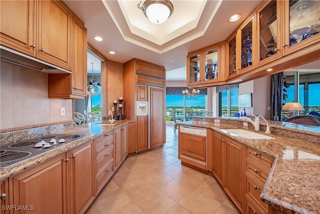 kitchen featuring light tile patterned flooring, paneled appliances, sink, a tray ceiling, and light stone countertops