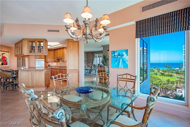 tiled dining room featuring a water view and a chandelier